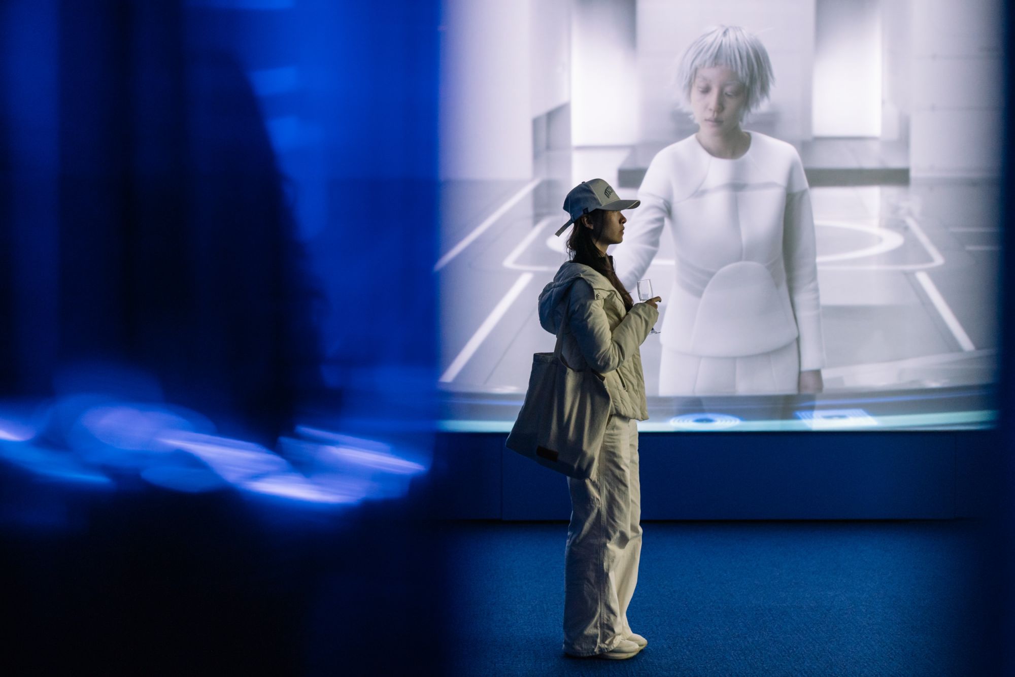 A young person with a baseball cap looks at arwork in a gallery
