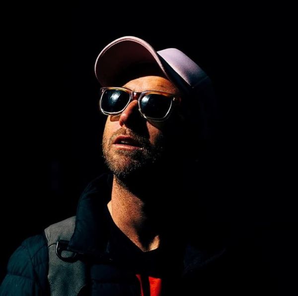 sunglasses and a mauve cap-adorned person with a black background