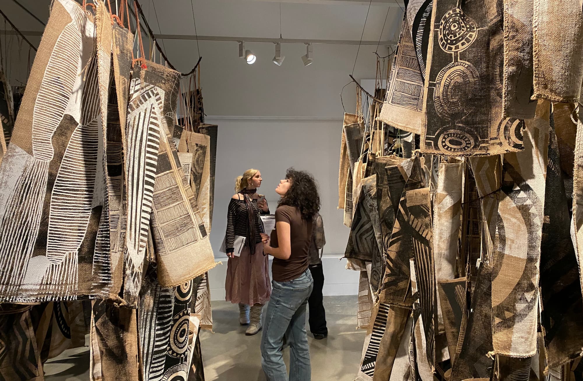 A student looks at printed bags hanging in a gallery wall