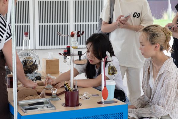 A student experienments with artwork at a table as others look on
