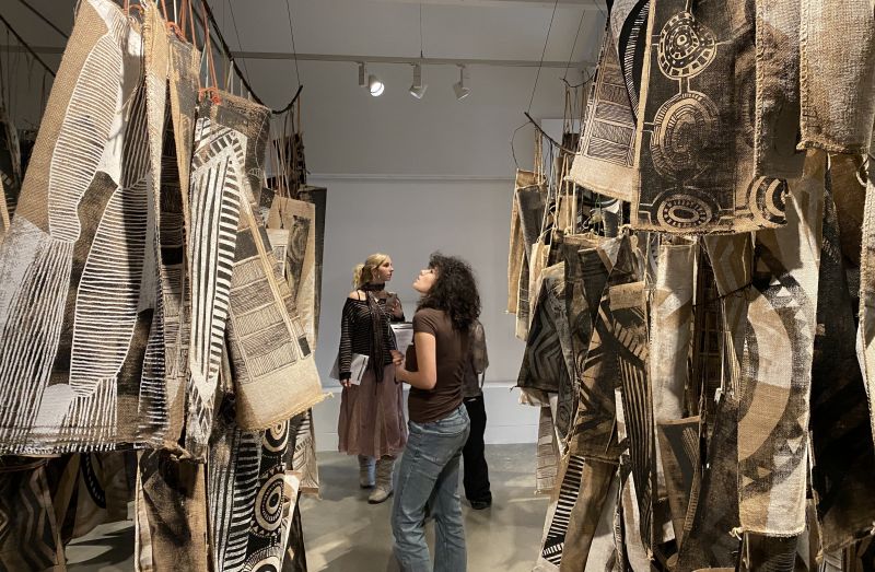A student looks at printed bags hanging in a gallery wall