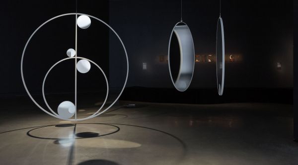 Lisa Sammut artwork with sculptural swinging moons hanging in a gallery
