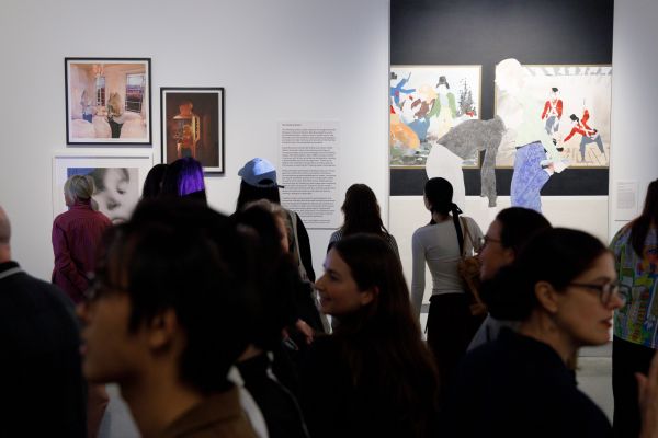 A group of people talking in a gallery with paintings in background