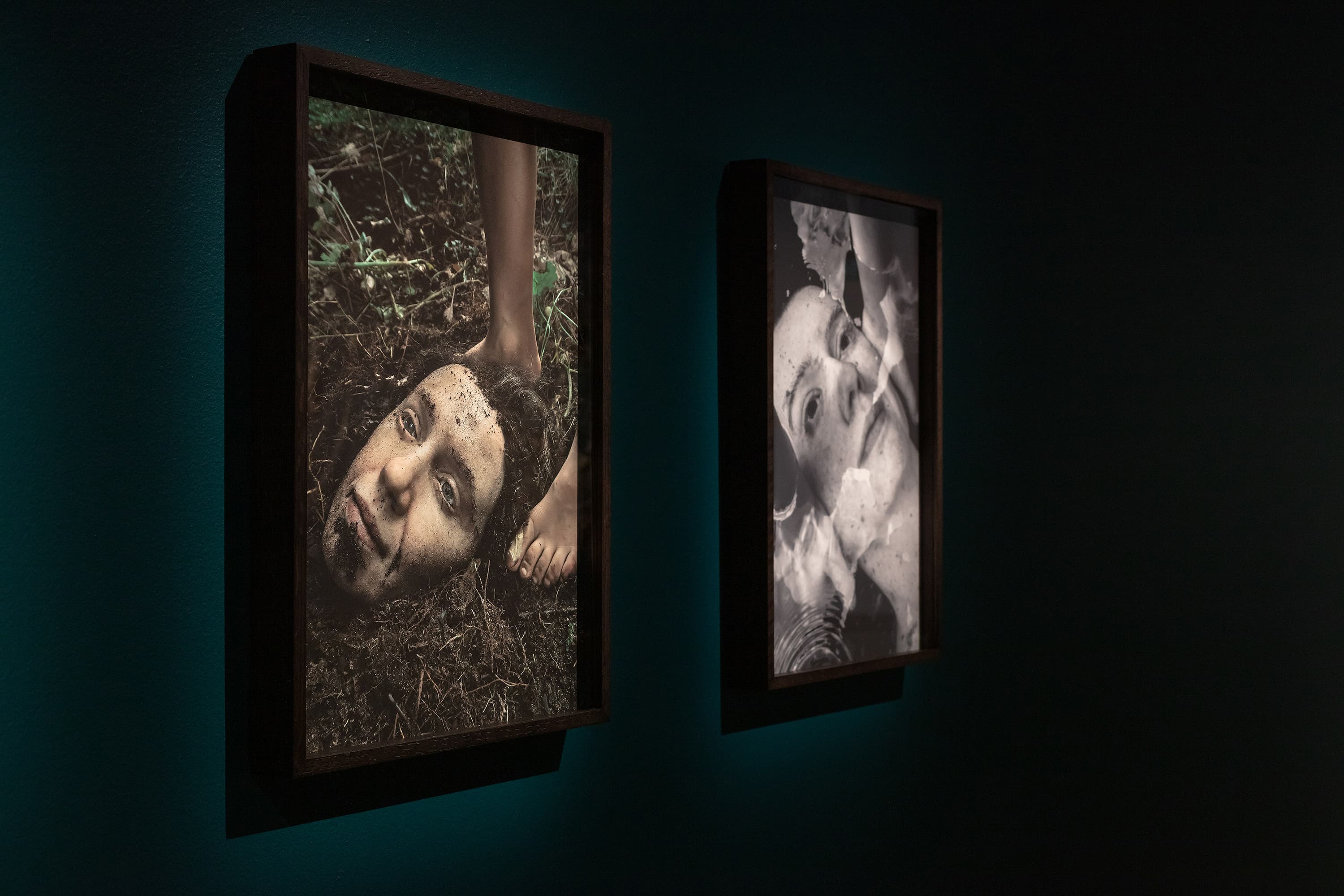 two photographs with a focus on heads on a wall in a gallery