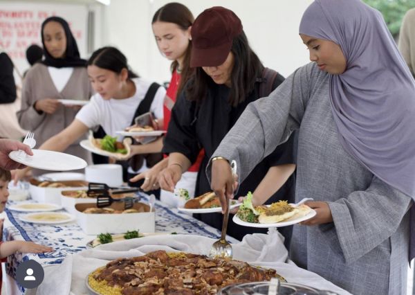 Women with head scarves line up to serve food onto plate